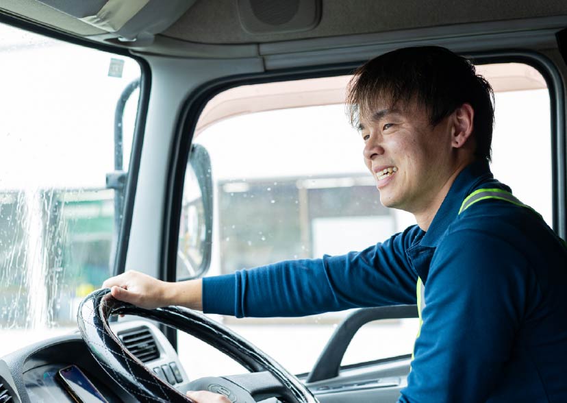 笑顔でトラックを運転する社員