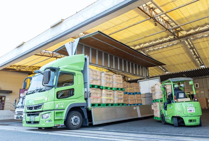倉庫でフォークリフトからトラックへ荷物を積み込む様子